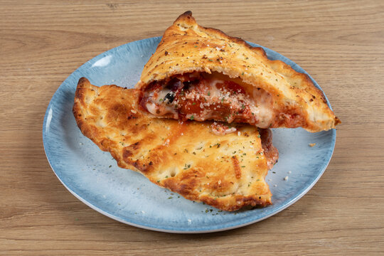 An Italian Calzone or Panzerotti cut in half to show the cheese and tomato sauce inside