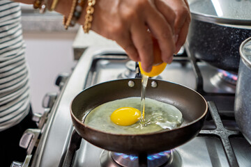 Fototapeta premium Hands cracking fresh egg into frying pan for breakfast