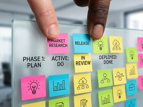 Hands organizing colorful sticky notes on a glass board, illustrating a project plan with phases like market research and release