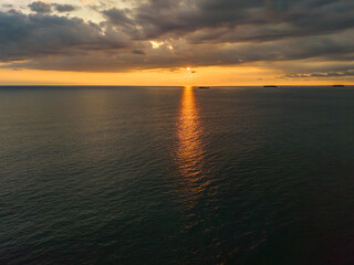 Obraz premium Golden sunlight dances on serene waters at sunset over the horizon, creating a tranquil atmosphere
