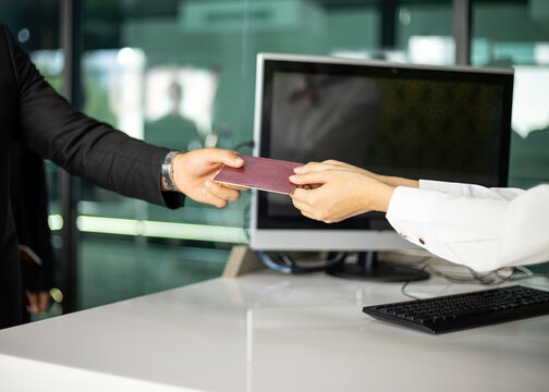 Close-up of business professional handing over passport at office counter for identity verification, travel document check and security screening in modern corporate customer service