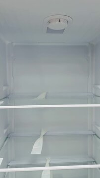 Empty refrigerator interior with glass shelves, bright LED lighting illuminating three tempered glass shelves and removable.