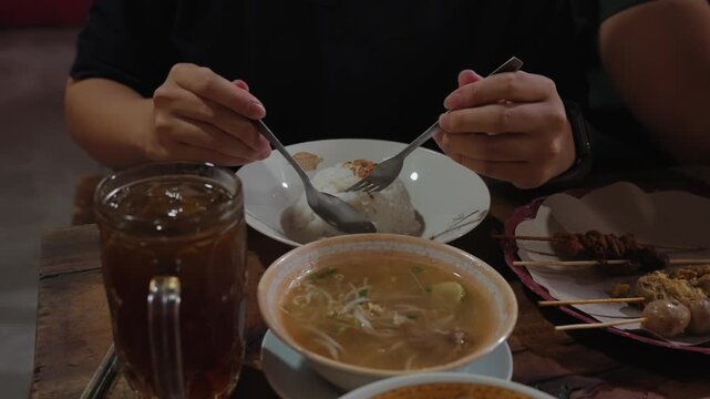 Traditional Indonesian meal featuring Soto Boyolali soup served with rice, quail egg satay, chicken intestine satay, and local street food snacks. Authentic culinary dining