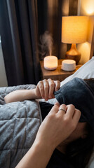 Relaxed person resting with a sleep mask in a cozy room, featuring a diffuser and lamp on the side table. The serene setting creates a calming atmosphere. Image made using Generative AI.