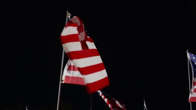 Night American flags waving under strong lights in Malibu, California, USA honoring September 11, rows of flags moving in wind creating powerful patriotic scene