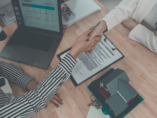 Real estate agents shake hands with clients after signing a contract for the sale of a property in an office setting. This concept is relevant to the real estate business.