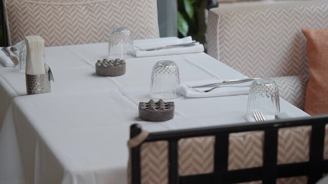 Elegant table setting at upscale outdoor restaurant with white linen and crystal glassware.