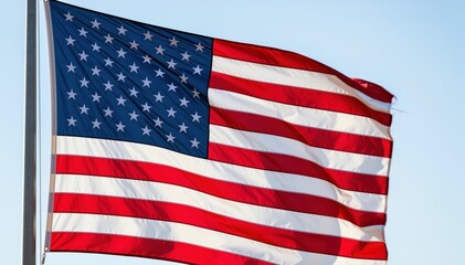 Fototapeta premium Symbol of Freedom: A vibrant American flag waves proudly against a clear sky, embodying the essence of liberty and national pride.