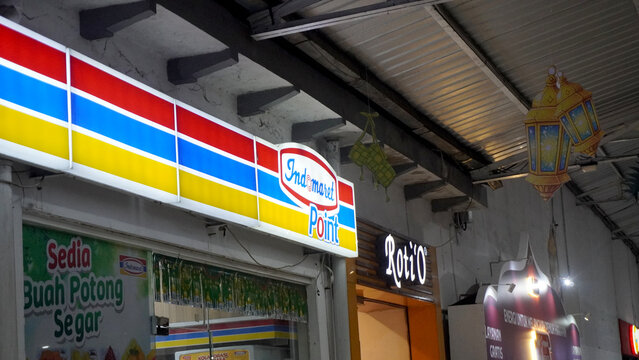 Purwokerto, Indonesia - 23 March 2026: Indomaret convenience store colorful signage with red, yellow, and blue stripes at indoor traditional market.