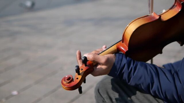 Man plays violin on city street in morning sunlight