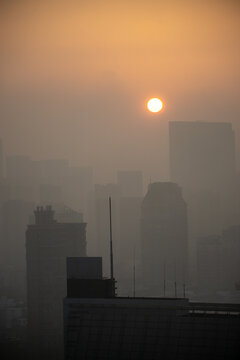 Pollution-blanketed urban sunrise or sunset, and the thick haze is caused by high levels of air pollution, specifically fine particulate matter, PM2.5
