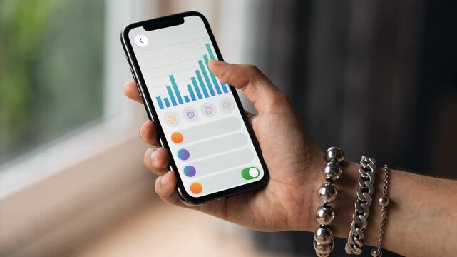Smartphone in hand showing an order entry screen on a mobile trading app with light mode main screen in clear focus rest softly blurred.