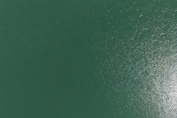 Green water surface aerial view showing ripples and sunlight reflecting on the aquatic texture © contentzilla
