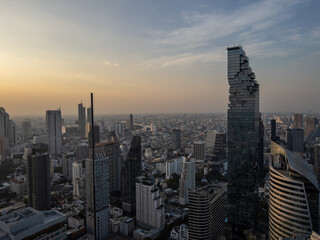 Stunning aerial vista of Bangkok, Thailand, at dusk, showcasing the iconic Mahanakhon Tower amidst a sprawling cityscape of modern high-rises and urban architecture. Golden hour light bathes the © BestTravelPhotos