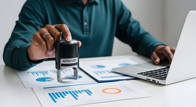 Approved stamp on business document with laptop for finance approval and document verification process