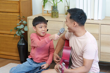 Fototapeta premium Father and son bonding through music and singing at home