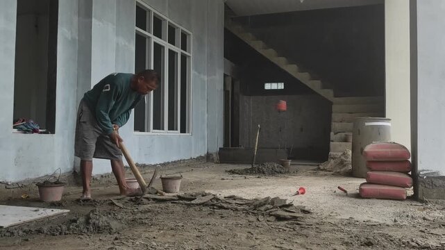 Construction worker leveling the ground surface using a traditional pickaxe hoe