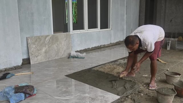 Handyman leveling wet cement mixture with a trowel for granite floor base