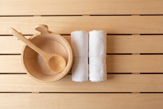 Wooden sauna bucket with ladle and rolled white towels