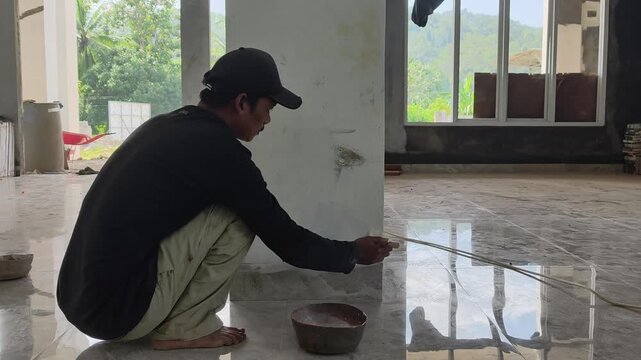 Construction worker painting structural poles with anti-rust coating at a building site