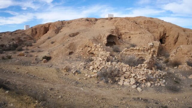 Panorama: Traditional troglodyte houses carved into rock in Matmata, Tunisia. Ancient underground dwellings in arid desert landscape, historic Berber architecture and cultural heritage site