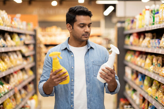 Man choosing between two different cleaning products while shopping in a supermarket