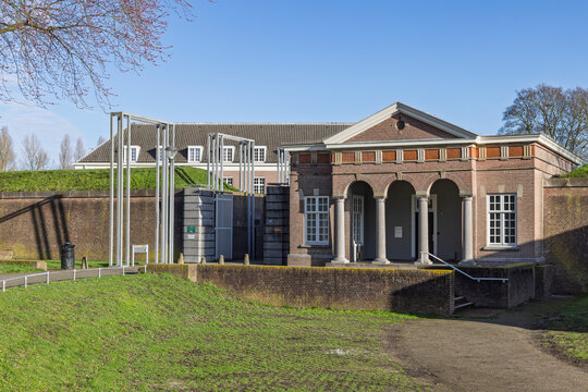 Neoclassical guardhouse building at the entrance of the Citadel fortress, surrounded by green grass and brick walls in Den Bosch, Netherlands.