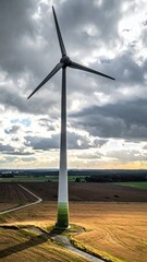 Obraz premium Wind Turbine Generating Clean Energy in Rural Landscape Under Dramatic Sky.