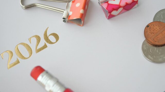 A close up view of a calculator, pencils, and clips next to 2026 caption on a white paper.