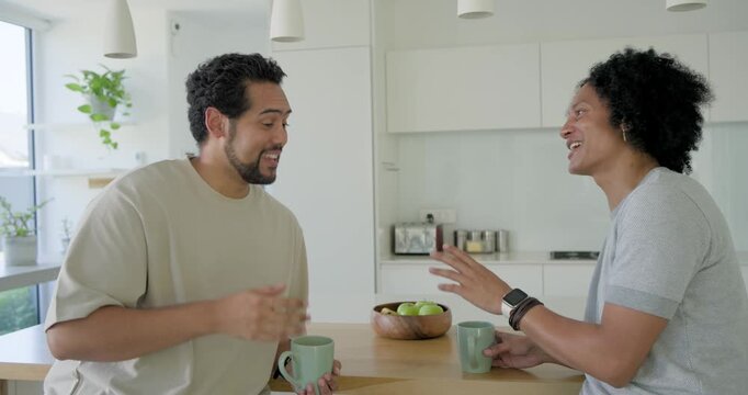 Diverse male friends talking, left friend sharing story, gesturing at kitchen island with mint mugs