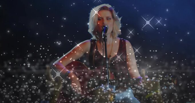 Sparkle overlay appearing while female performer singing into mic and strumming guitar for crowd