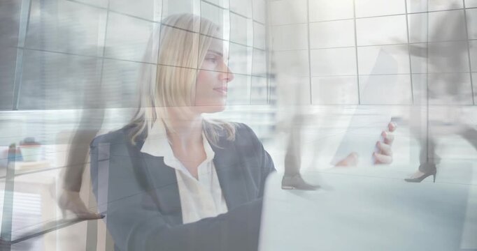 Office woman sitting at desk, walking figures passing, causing phone checking and refocusing laptop