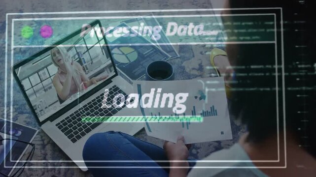 Seated person holding chart, watching laptop as remote host sharing data, HUD loading for business