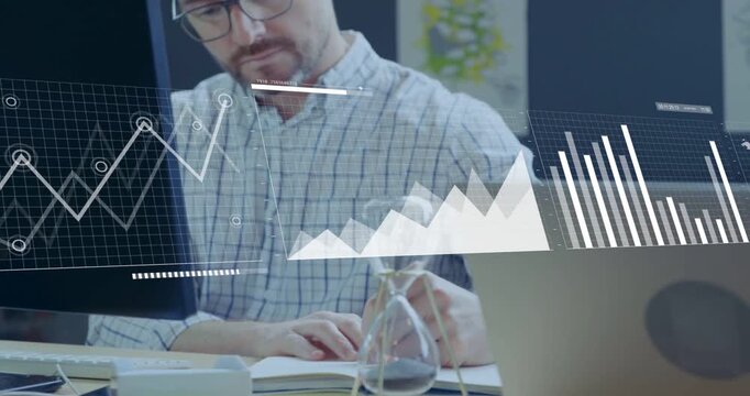 Vertical video: Typing man in plaid shirt holding hourglass at desk with HUD emerging tracking data