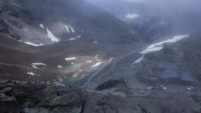 Aerial drone tilts up over rocky terrain at Sach Pass, revealing the dangerous road from Chamba valley to Pangi valley in Himachal Pradesh.