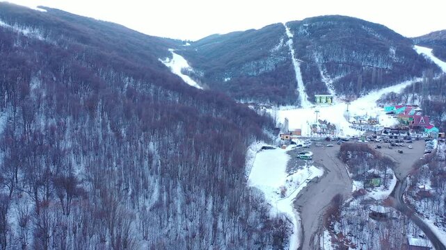Snow-covered mountain slopes descend into a deep valley where winter textures and shadowed ridgelines define a cold alpine environment