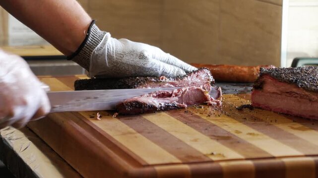 Slicer carves juicy lean Texas barbecue smoked brisket, carefeully slicing tender beef brisket for bbq plates, slow motion 4K