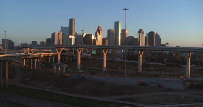 A sweeping establishing drone shot capturing the iconic downtown Houston skyline as the setting sun casts a golden glow across the towering skyscrapers, creating a dramatic and vibrant urban landscape
