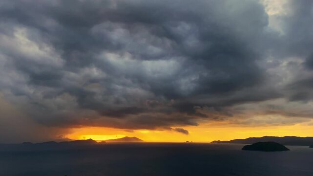 Aerial time-lapse of massive dark storm clouds forming over the ocean during a golden sunset. A dramatic meteorological display showing pre-typhoon weather patterns over sea and islands
