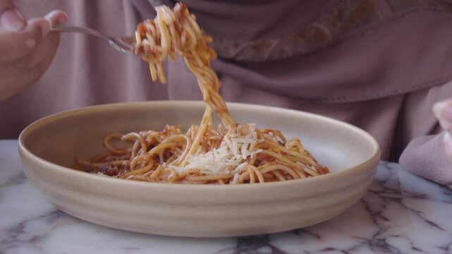 A person rotating spaghetti with a fork and lifting it from plate in slow motion video clip.