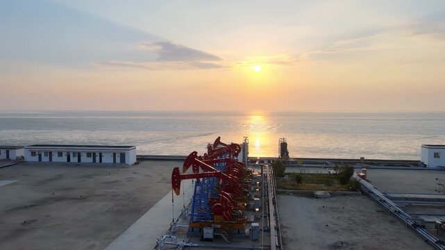 The change oil gasoline prices caused by war, golden sunset shining behind crude oil drilling rigs derrick, pump jack machine oilfield, continuous extraction of fossil fuels global energy consumption