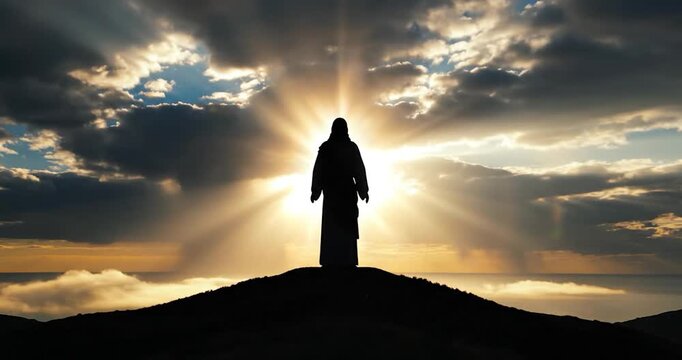 Silhouette of Jesus Christ Standing on a Mountain at Sunset