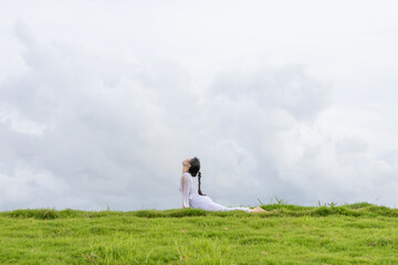 Fototapeta premium A Chinese woman practicing yoga on the grass