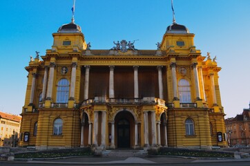 Fototapeta premium Historic theater building in Zagreb illuminated by warm sunlight showcasing classical European architecture