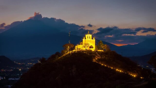 Illuminated church on hill at sunset with Popocatepetl volcano in Atlixco, Puebla, Mexico