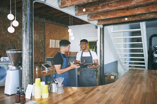 Waiter, men and talking with tablet in restaurant for barista training, order entry and POS system. Small business, team and manager with cafe app to explain online inventory, menu update or planning