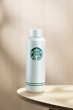 Minimalist insulated bottle with Starbucks logo placed on a wooden table, clean background, modern lifestyle concept, reusable drinkware and eco-friendly trend.