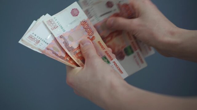 A businessman in a white shirt is counting Russian paper money in denominations of one thousand and five thousand rubles. Man counts paper 5000, 1000 rubles bills. Russian cash money in male hand. 