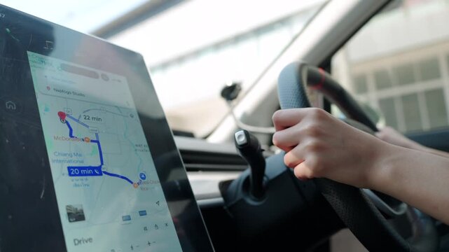 Asian woman interacts with a modern car's touch screen navigation system for route planning. GPS map, destination, convenient driving technology concept.