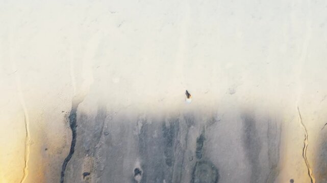 Dirty and dusty dark window glass in the sunset. Abstract dirty window glass background. Window with very dirty and dusty glass in daylight in the sunset. Condensation on the fogged windows glass.